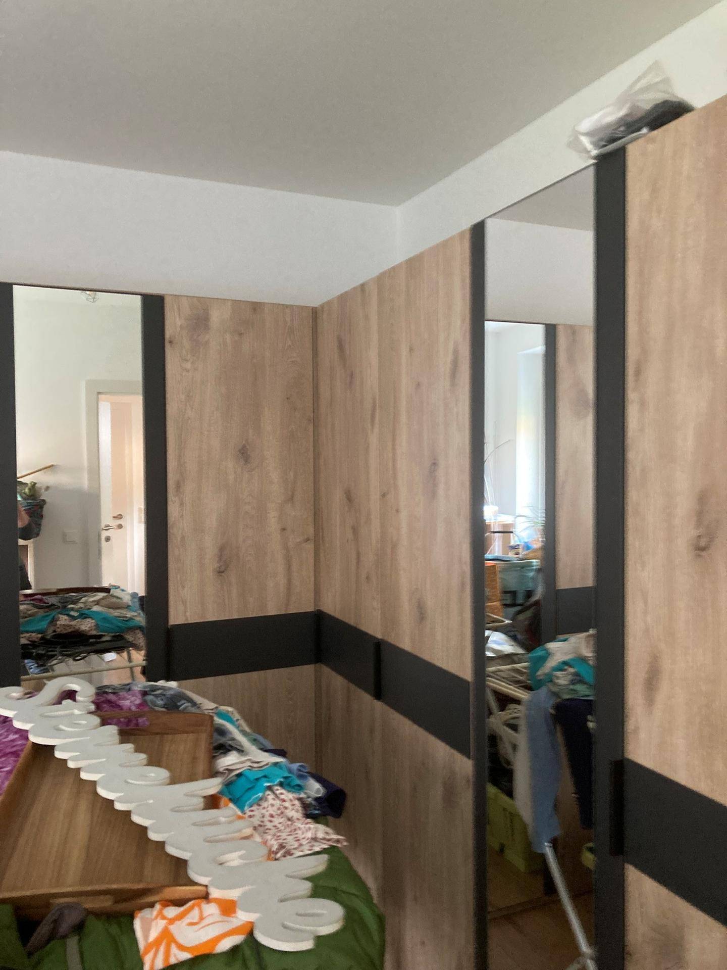 Schlafzimmer mit großem Spiegelschrank und Holzoptik, bietet viel Stauraum.