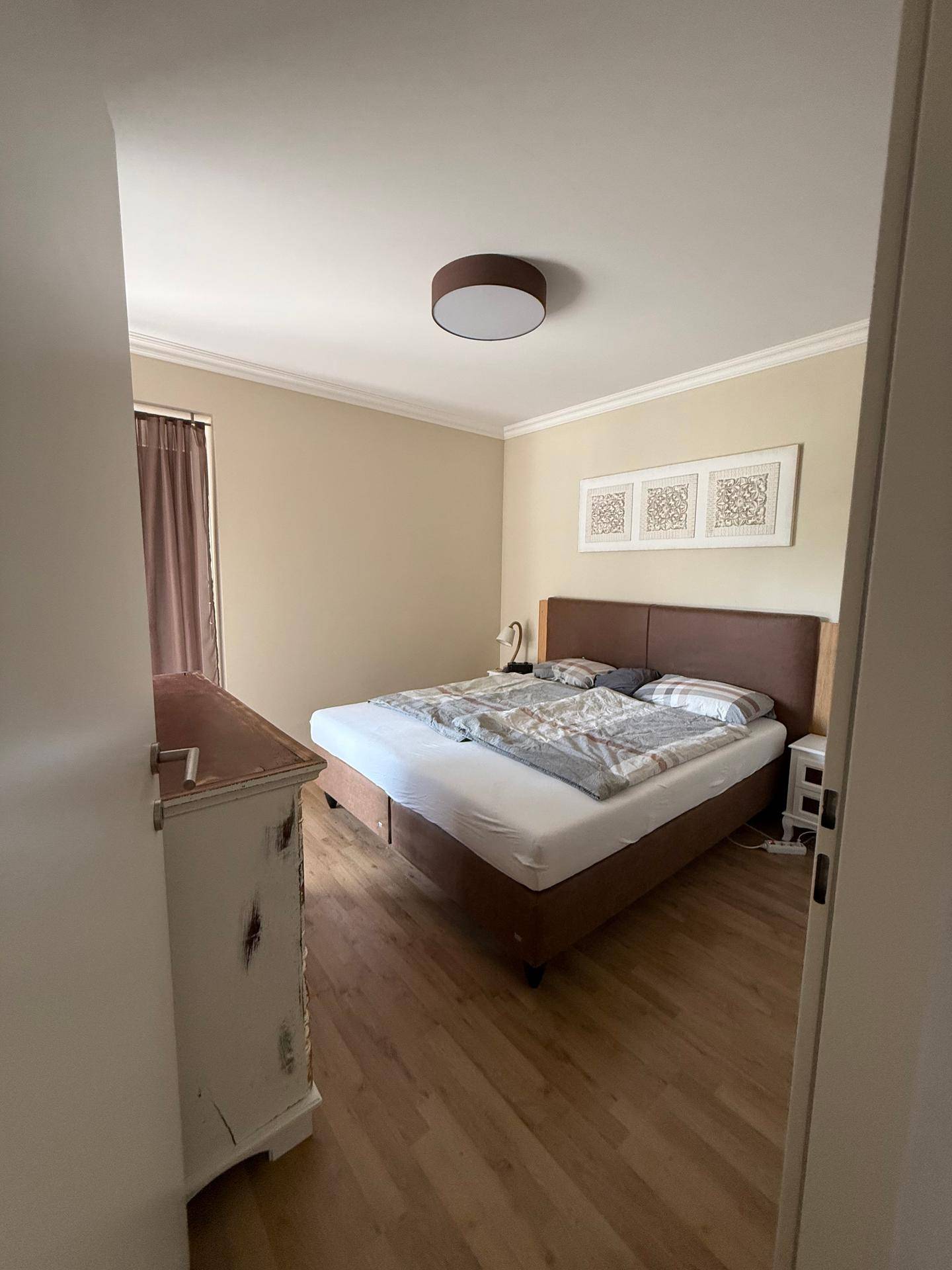 Schlafzimmer mit Doppelbett, Nachttischen und hellem Laminatboden.