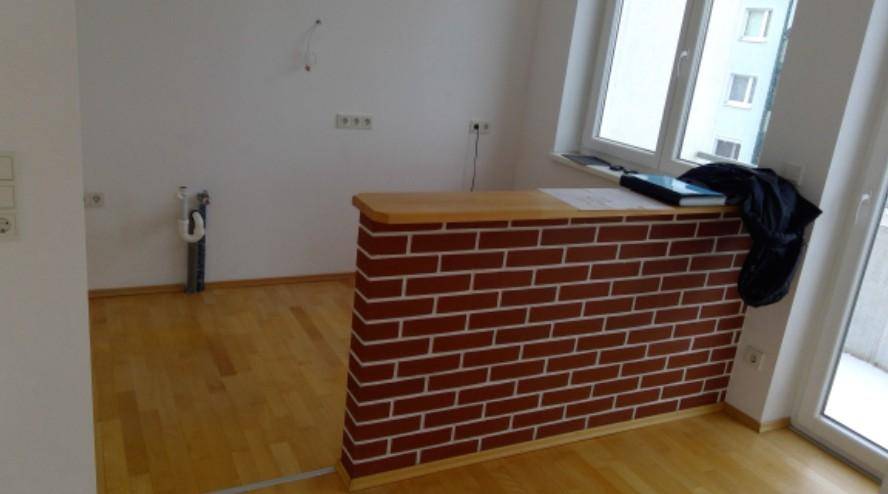 Bereich für eine Küche mit vorbereiteten Anschlüssen und einer gemauerten Theke, ideal für eine offene Gestaltung.