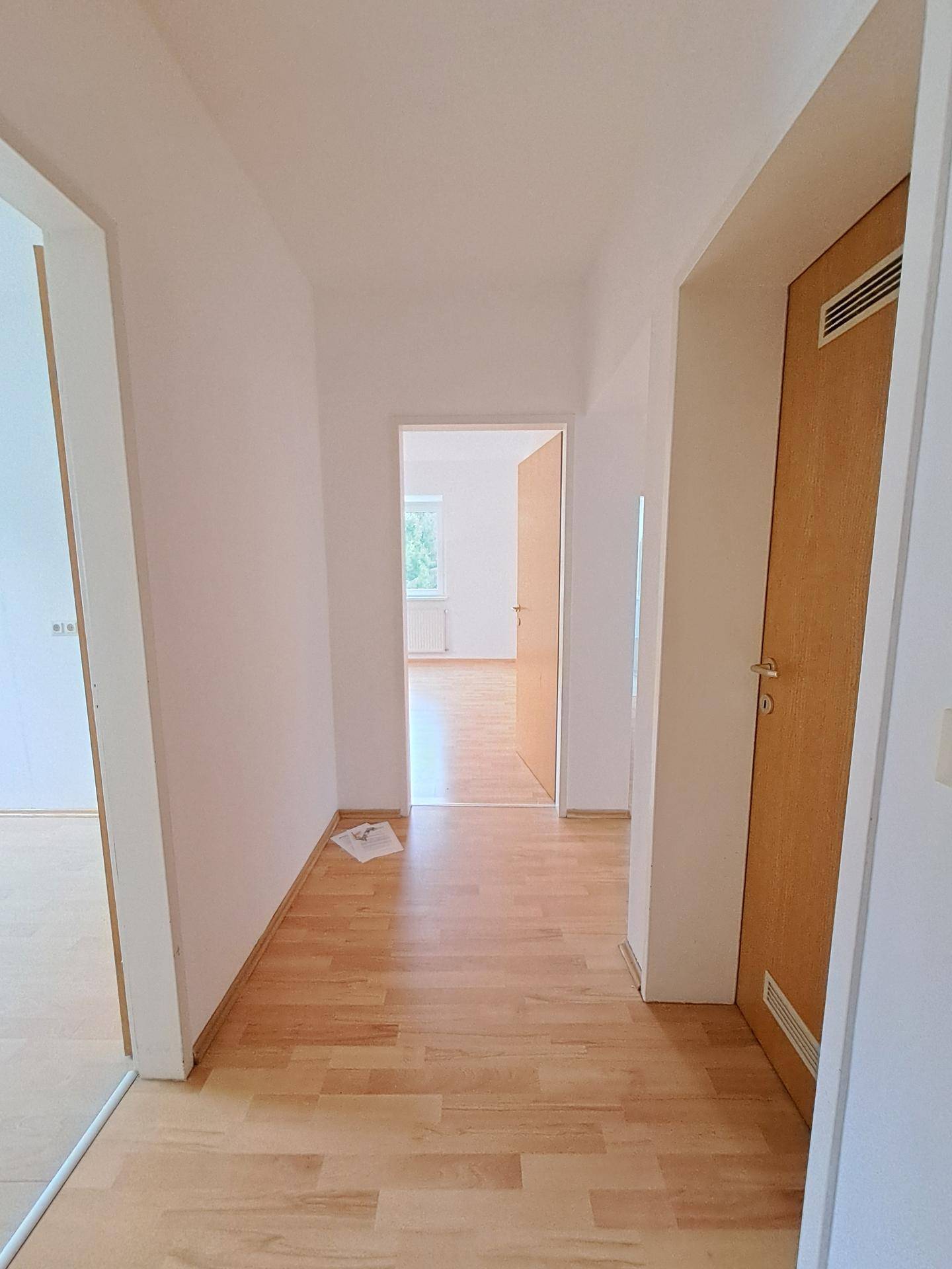 Heller Flur mit Laminatboden und mehreren Türen, die zu verschiedenen Zimmern der Wohnung führen.