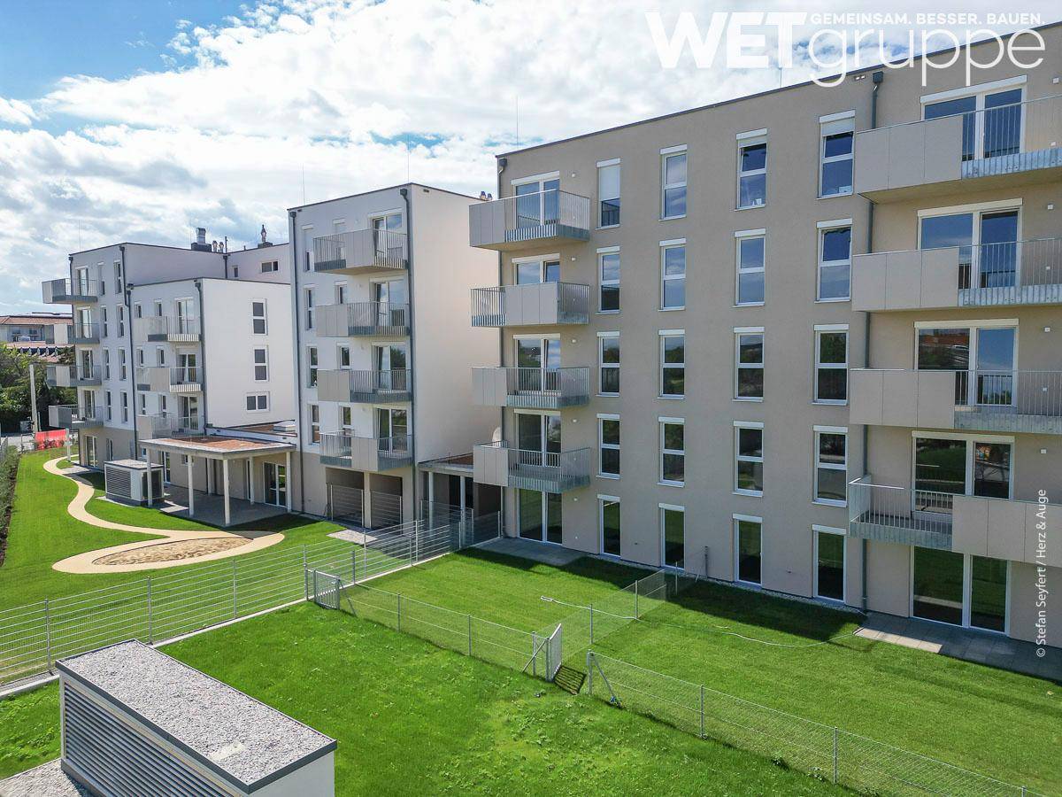 Moderne Wohngebäude mit Balkonen und weitläufigen Grünflächen in einer gepflegten Anlage.