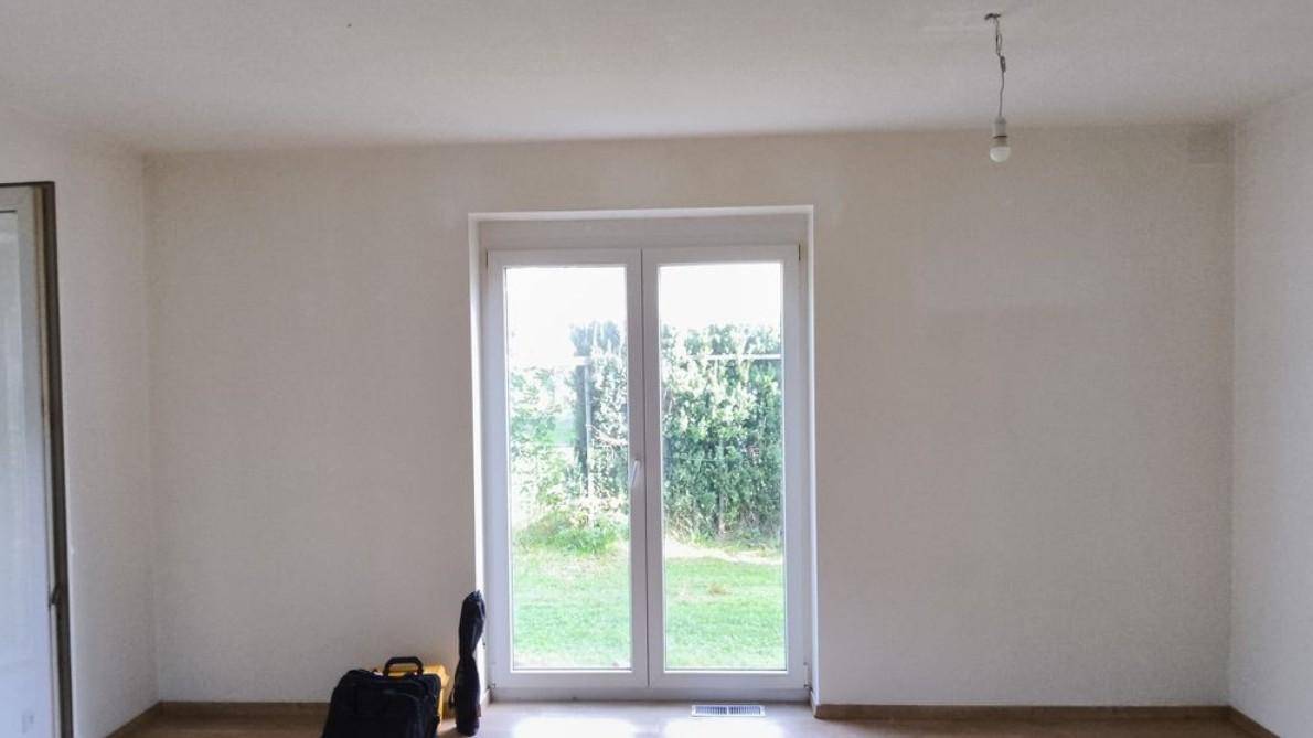 Heller, leerer Raum mit großem Fenster und direktem Zugang zum Gartenbereich.