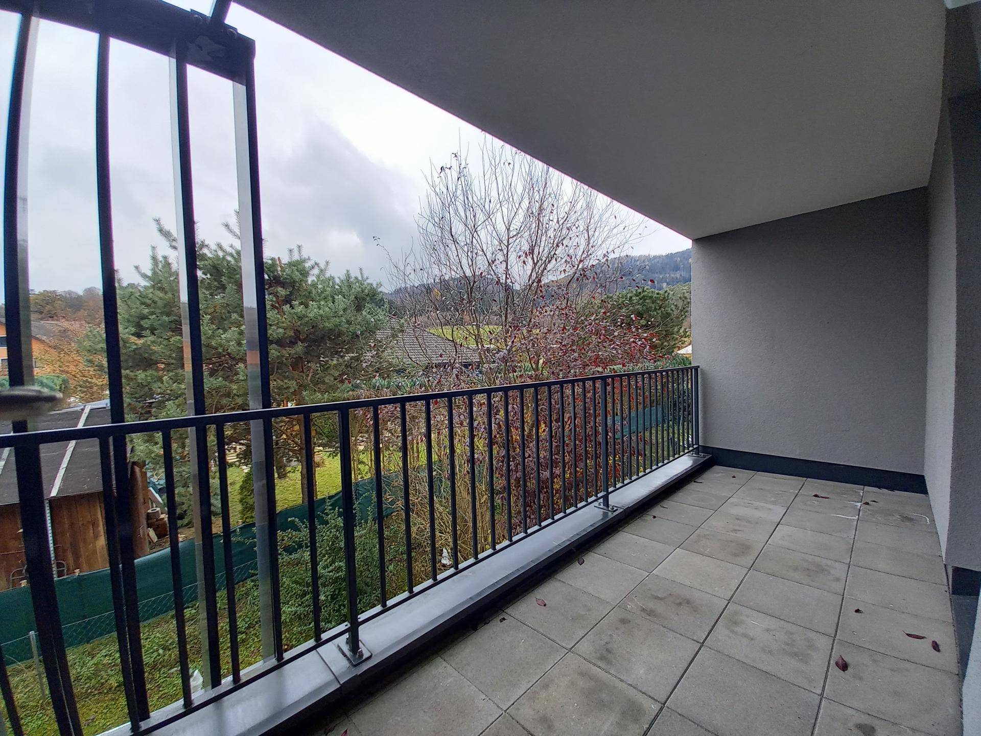 Geräumiger Balkon mit Fliesenboden und Blick ins Grüne und auf die Berge.