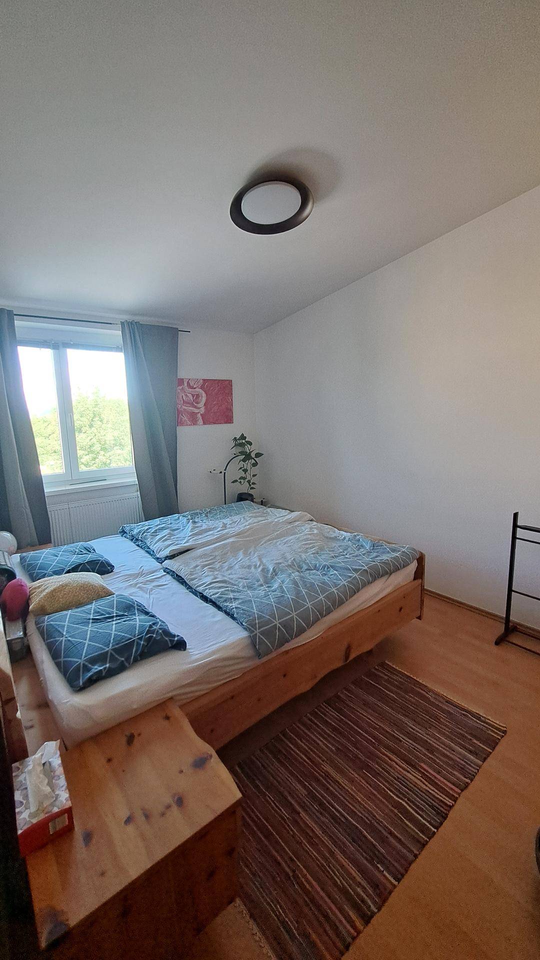 Schlafzimmer mit Doppelbett, Holzmöbeln und Fenster mit Blick ins Grüne.