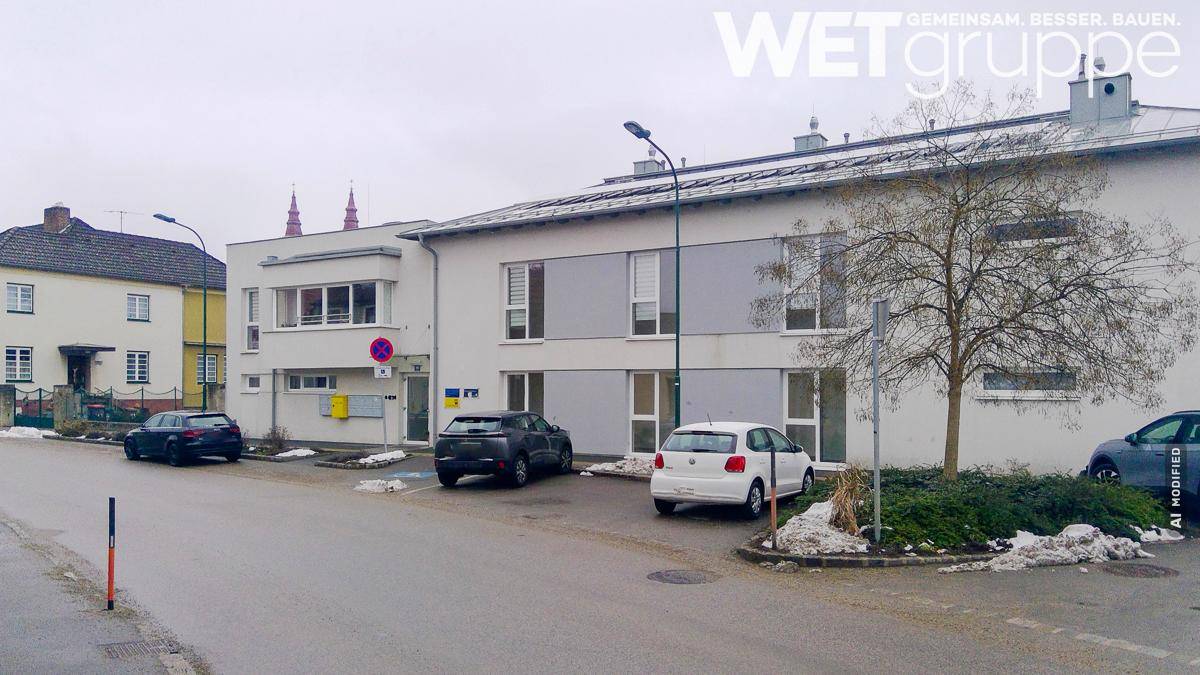 Wohngebäude in städtischer Umgebung mit Parkplätzen und umliegenden Häusern.