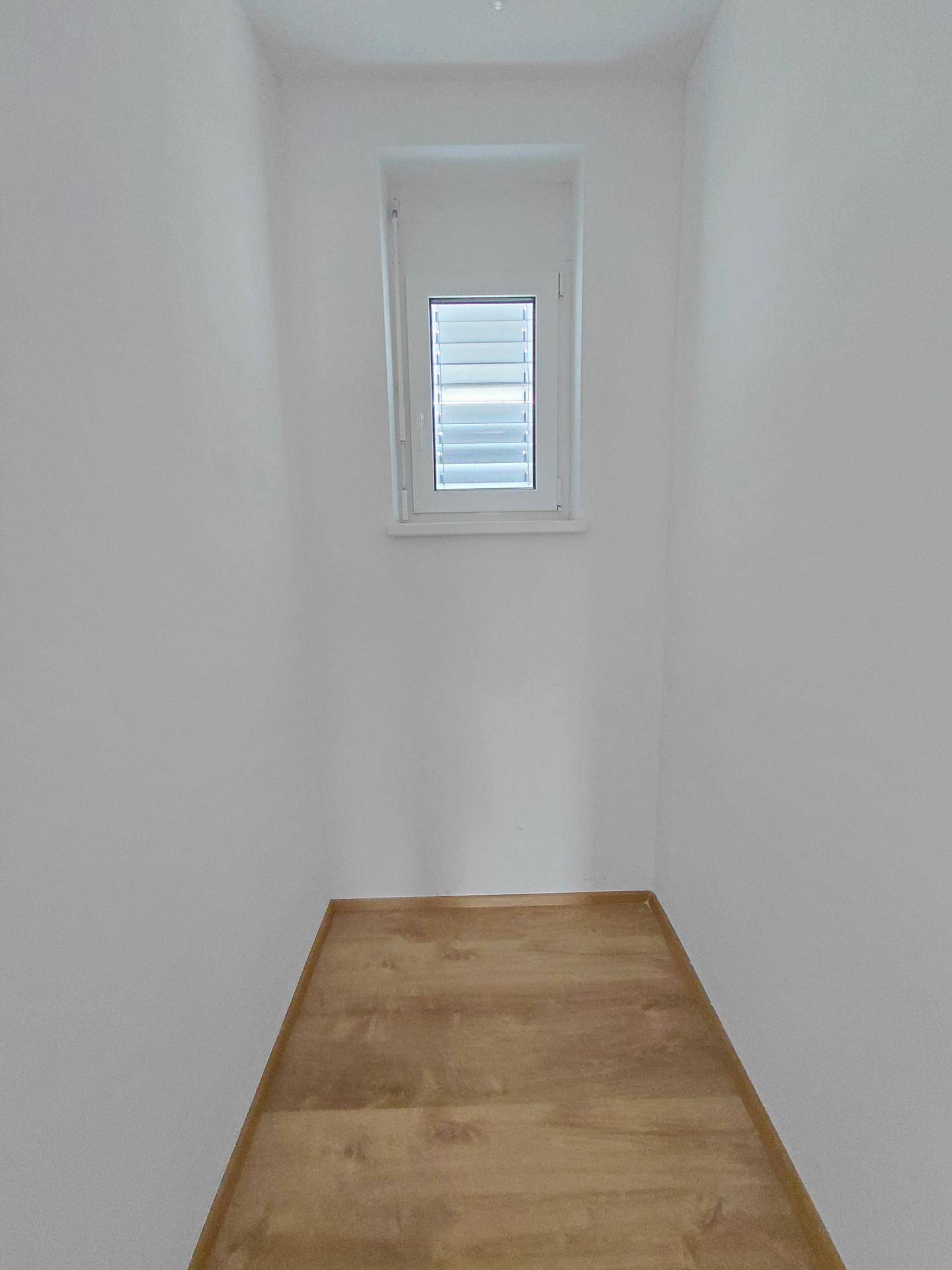 Kleiner Abstellraum mit Fenster und Laminatboden, ideal für zusätzlichen Stauraum.