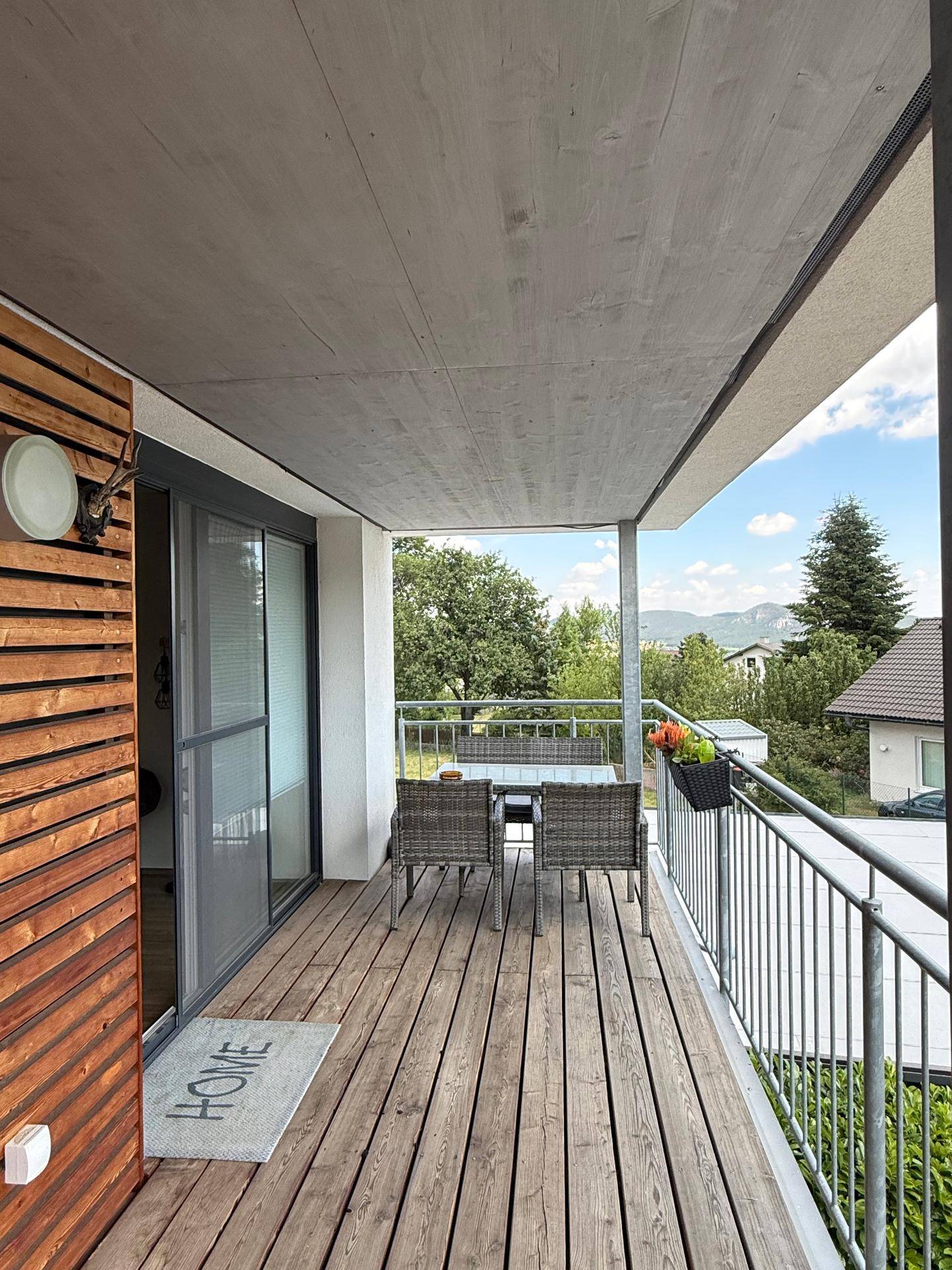 Möblierter Balkon mit Holzboden und weitem Blick auf die umliegende Landschaft.