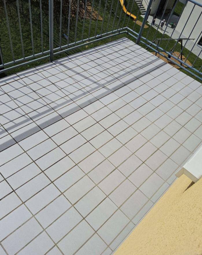 Gefliester Balkonboden mit Metallgeländer, ideal für sonnige Stunden im Freien.