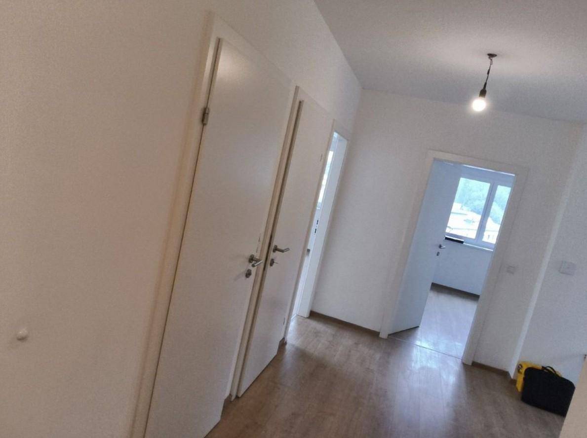 Heller Flur mit Laminatboden und mehreren Türen zu den angrenzenden Räumen.