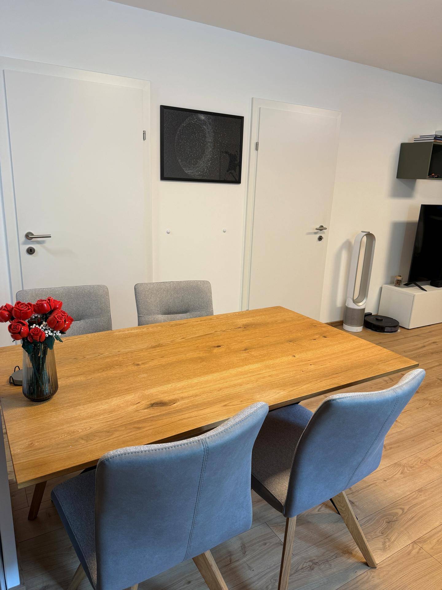 Heller Essbereich mit Holztisch und modernen Stühlen, umgeben von weißen Türen.