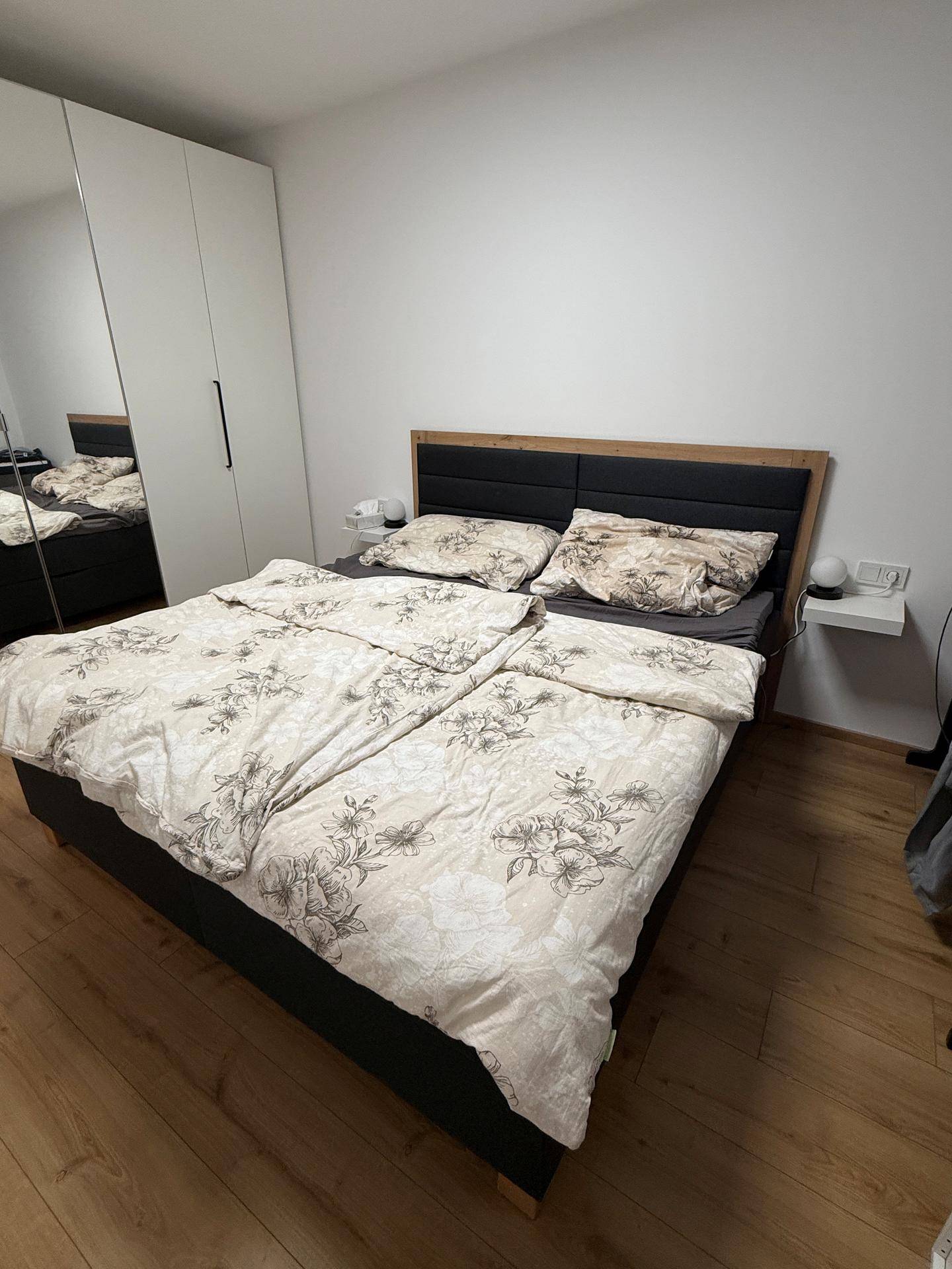 Schlafzimmer mit Doppelbett, weißem Kleiderschrank und Laminatboden.