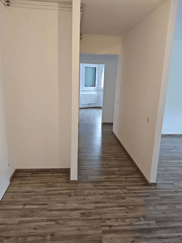 Heller Flur mit Laminatboden, der zu weiteren Zimmern führt und Tageslicht erhält.
