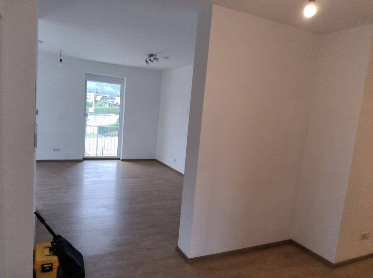 Lichtdurchfluteter Wohnbereich mit Laminatboden und direktem Zugang zum Balkon.