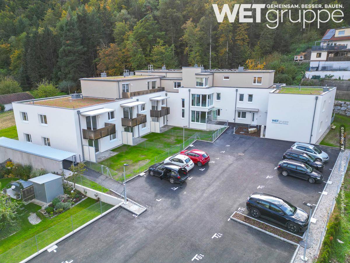 Luftaufnahme des Wohnkomplexes mit Parkplätzen und umliegenden Grünflächen in ländlicher Umgebung.