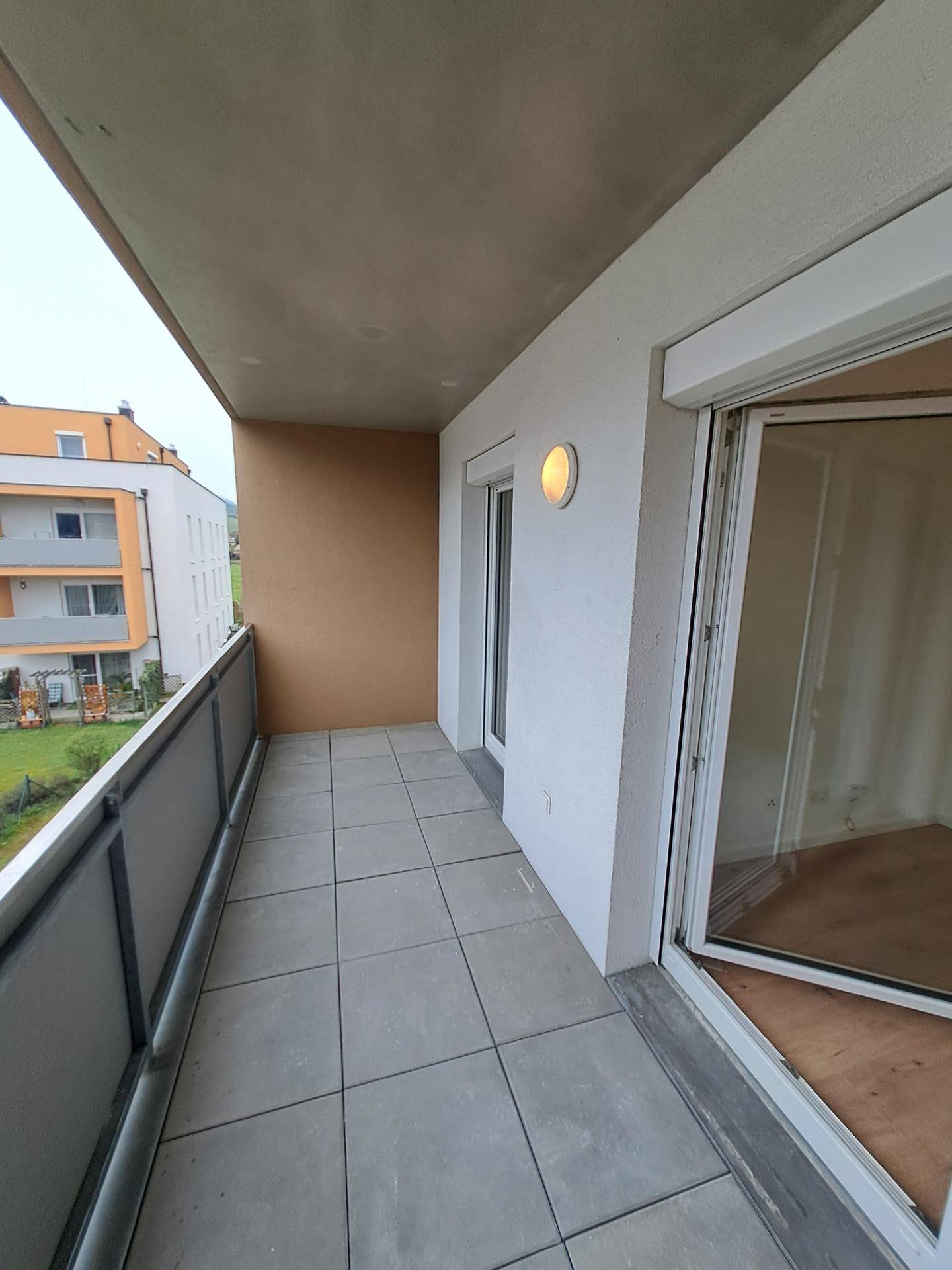 Geräumiger Balkon mit grauen Fliesen und Blick auf die umliegende Wohnbebauung.