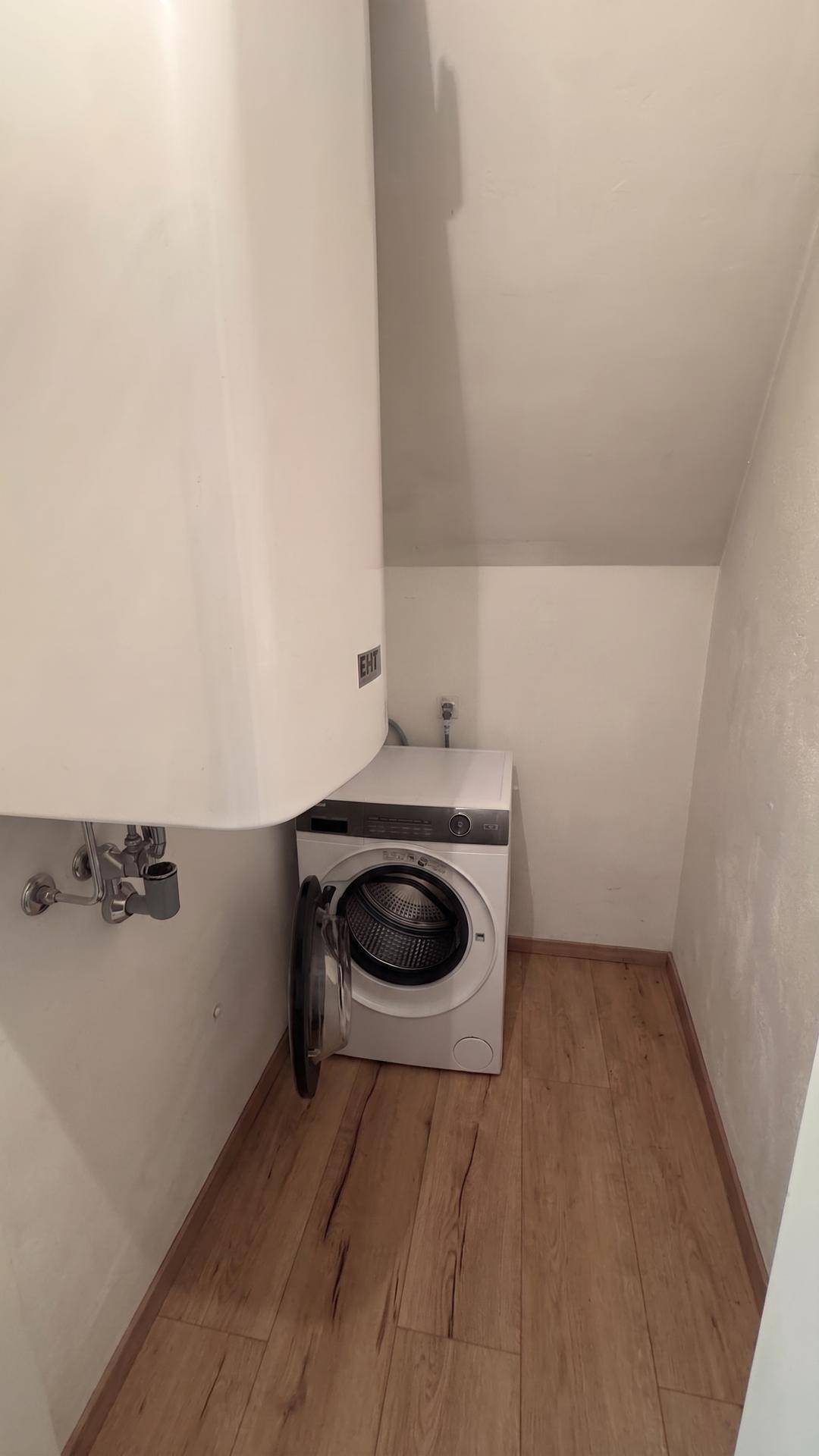 Praktischer Hauswirtschaftsraum mit Waschmaschine und Warmwasserboiler im Dachgeschoss.