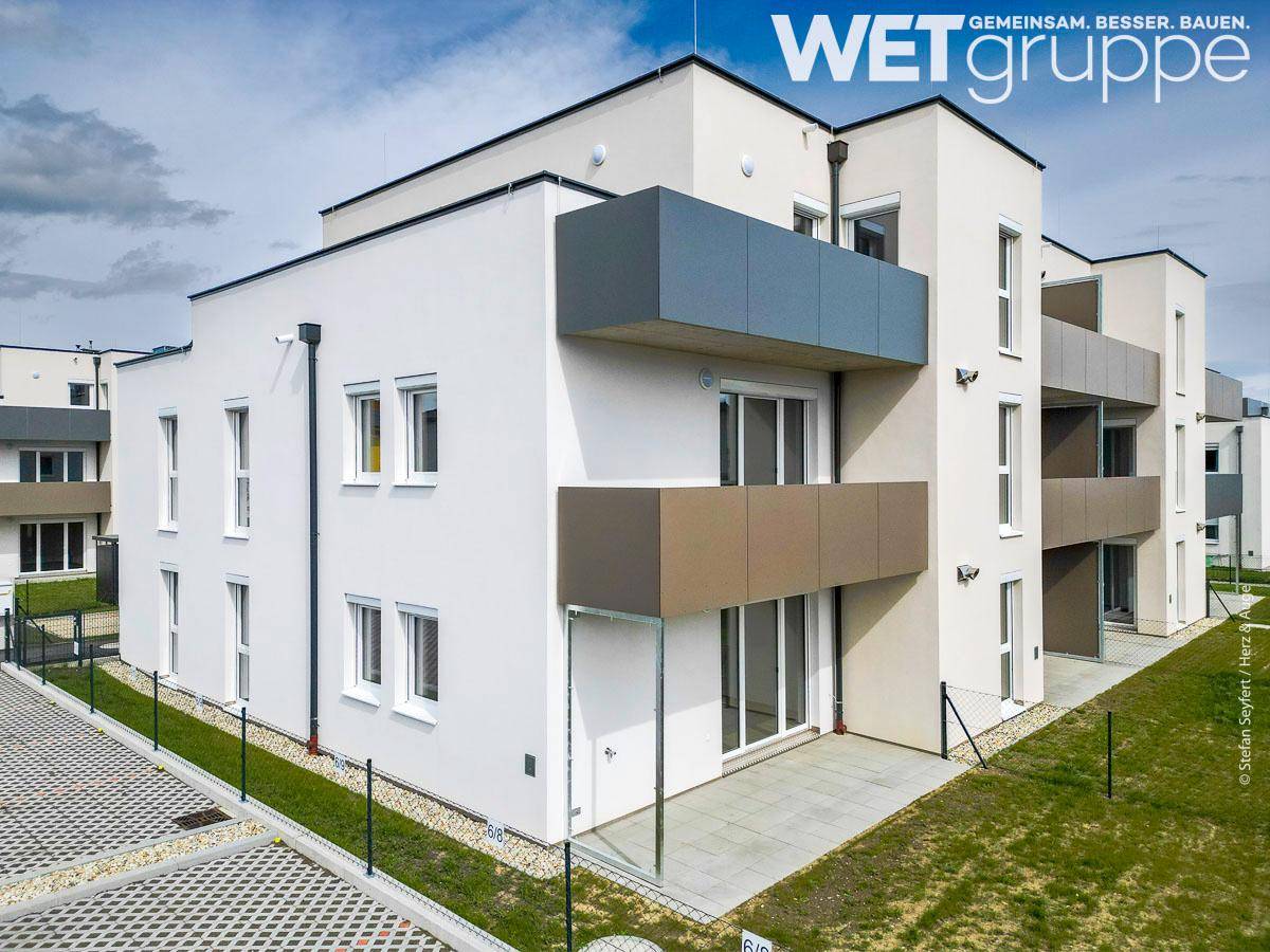Ansicht eines modernen Wohnhauses mit weißer Fassade und braunen Balkonen.