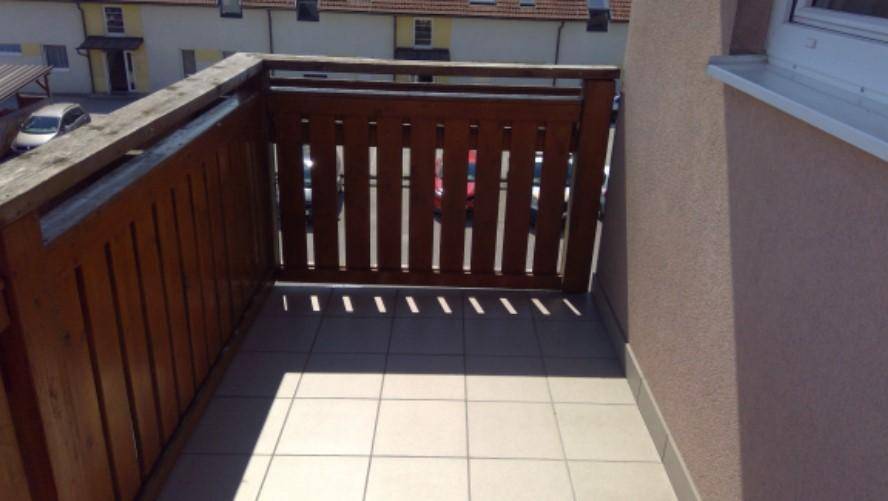 Kleiner Balkon mit Holzbalkonbrüstung und Fliesenboden, ideal für entspannte Stunden im Freien.