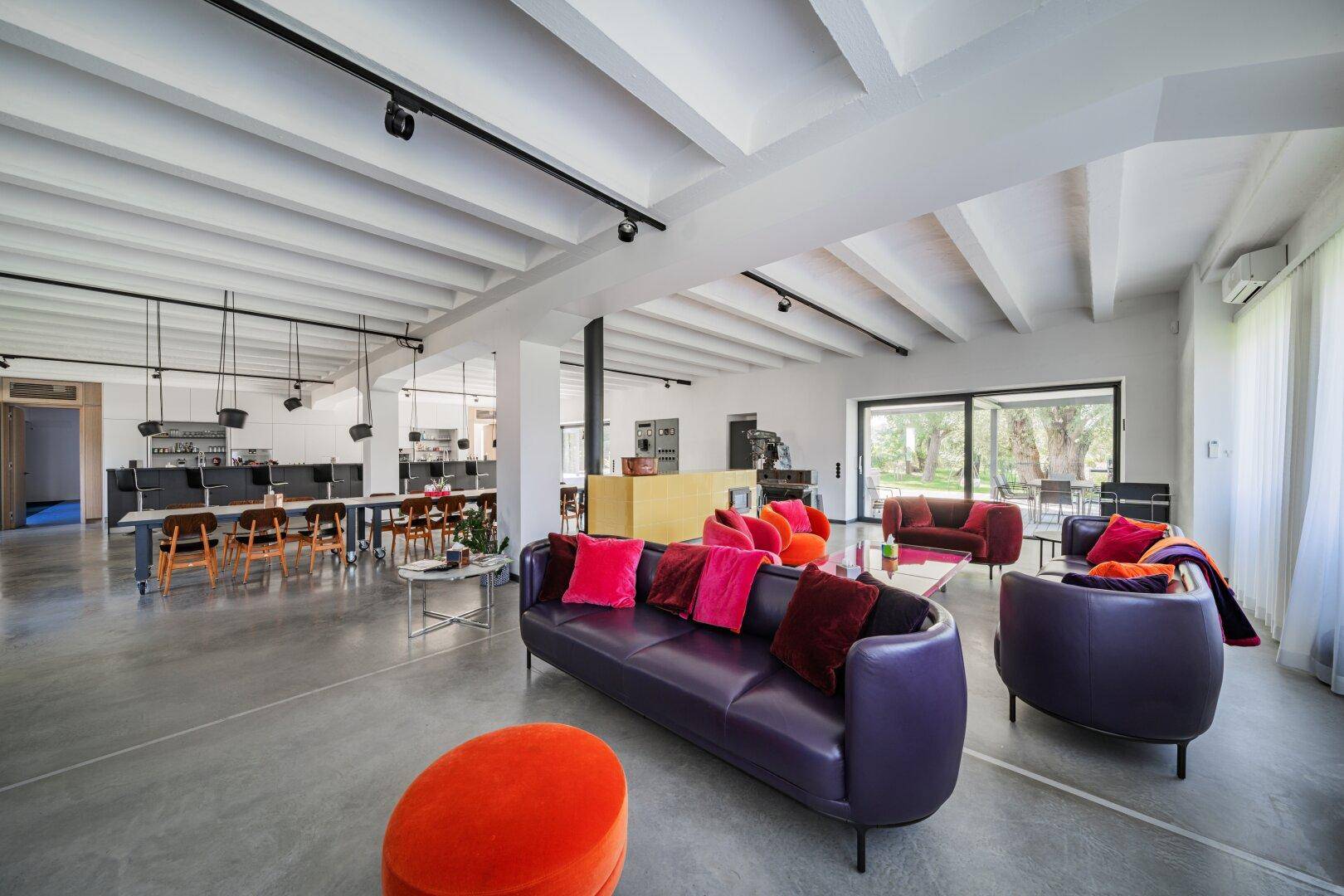 Heller, offener Wohnbereich mit farbenfrohen Sofas, hohen Decken und Zugang zur Terrasse.