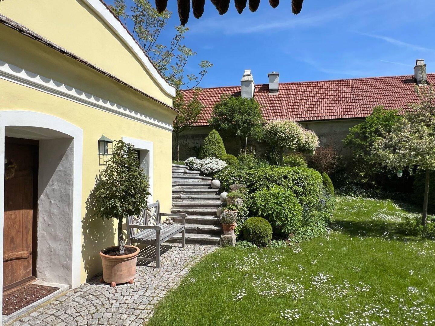 Gepflasterter Weg führt zu einer Steintreppe in einem liebevoll gestalteten Gartenbereich.