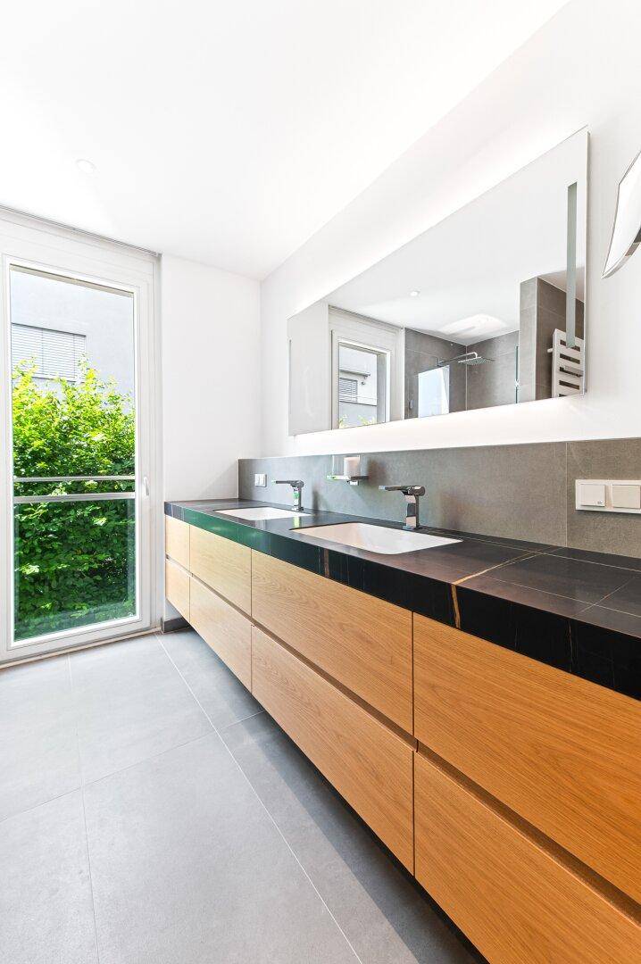 Modernes Badezimmer mit Doppelwaschbecken, großem Spiegel und Fenster für Tageslicht.