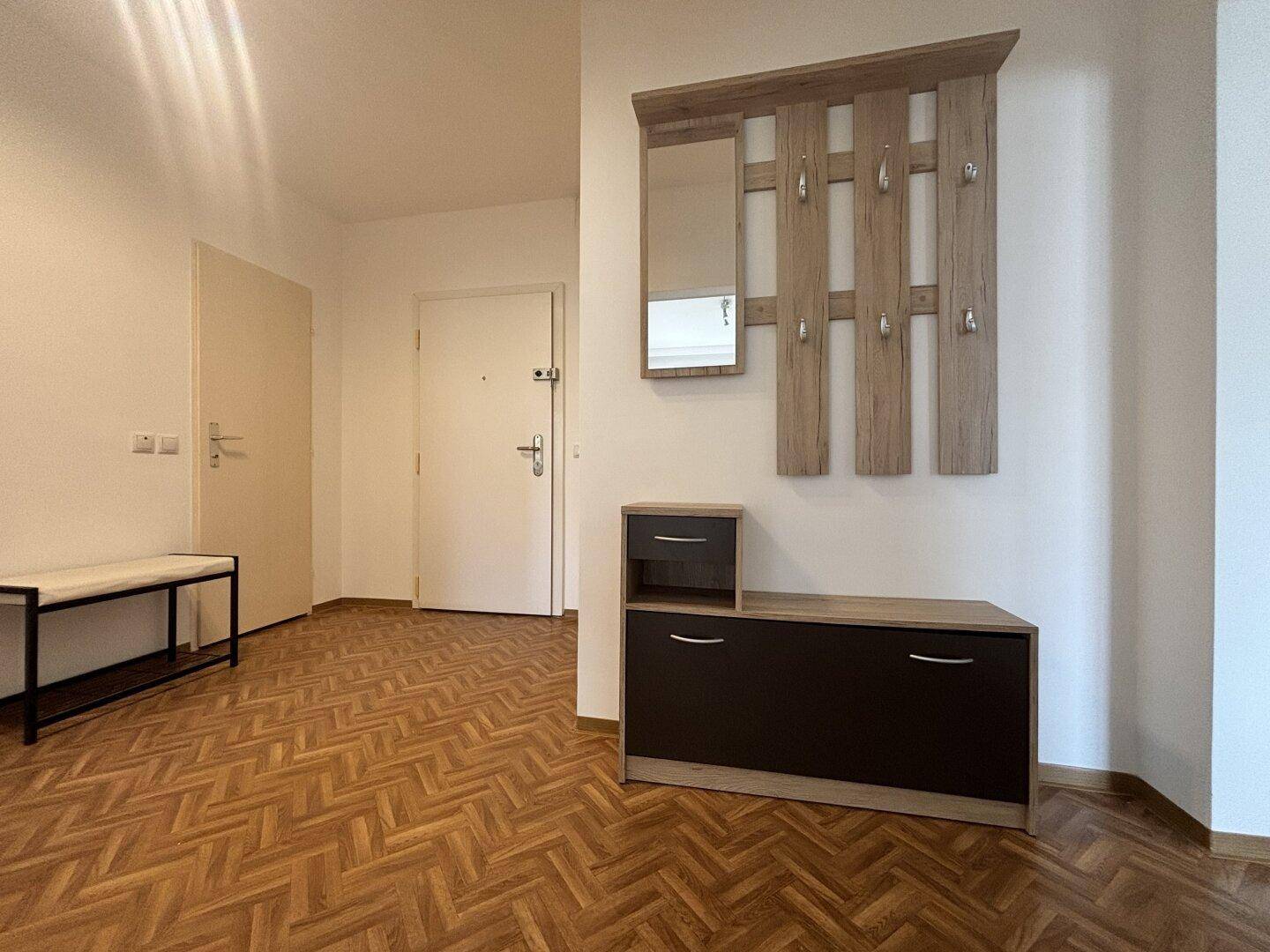 Heller Eingangsbereich mit Parkettboden, Garderobe und Schuhschrank.