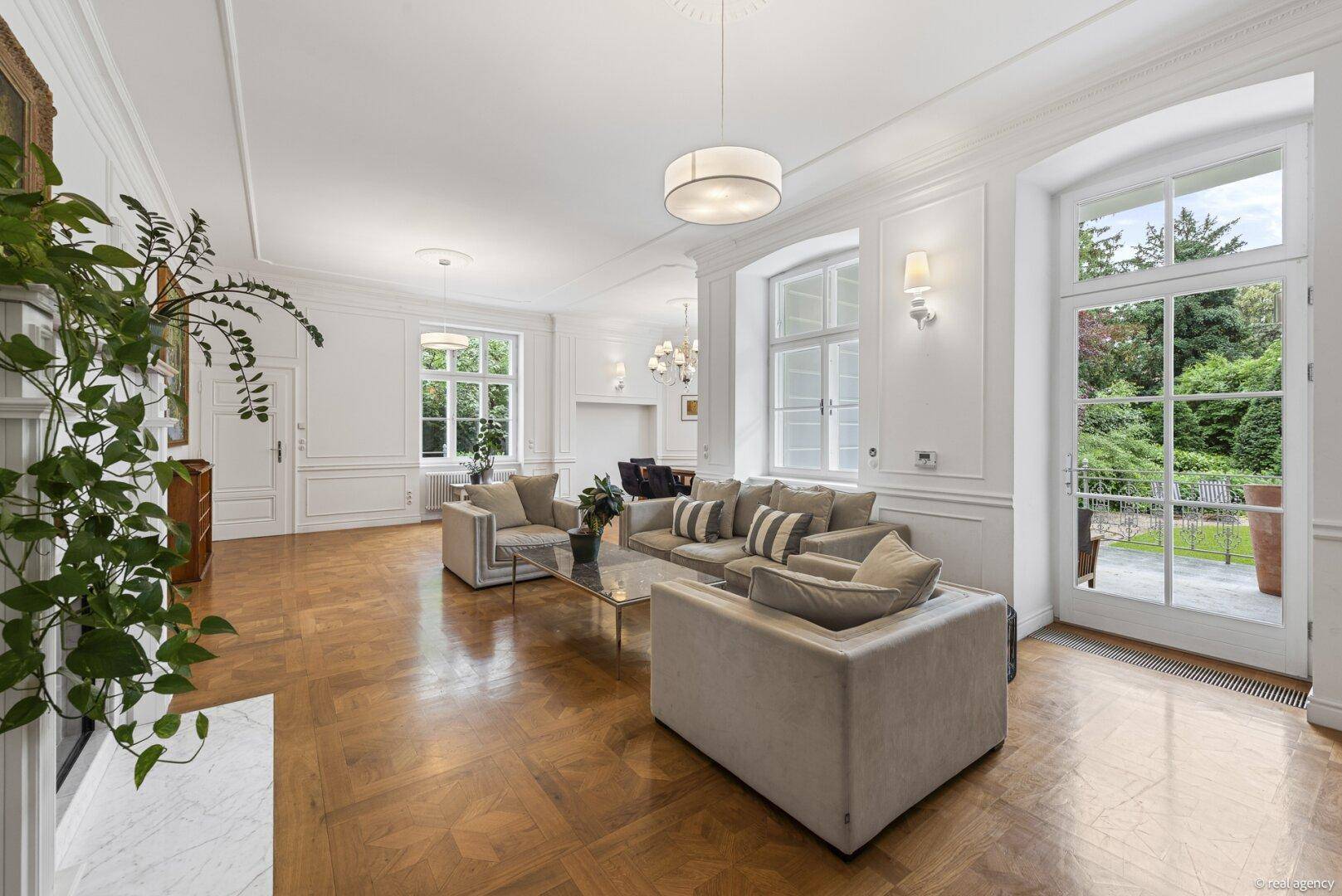 Geräumiges, helles Wohn- und Esszimmer mit elegantem Parkettboden, hohen Decken und direktem Zugang zum Garten.