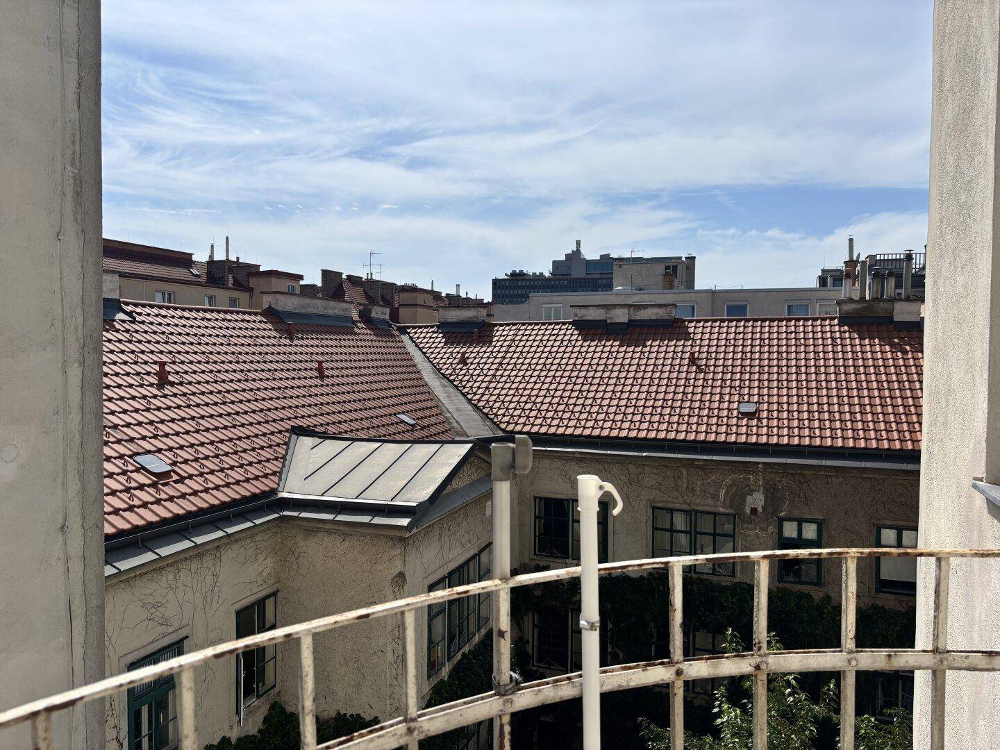 Blick über die roten Ziegeldächer der umliegenden Gebäude von einem Balkon im Innenhof.