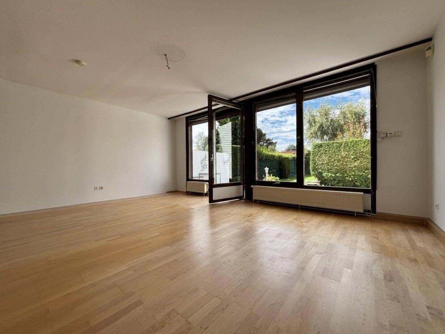 Geräumiges Wohnzimmer mit Eichenparkett und viel Tageslicht durch die großen Fenster.