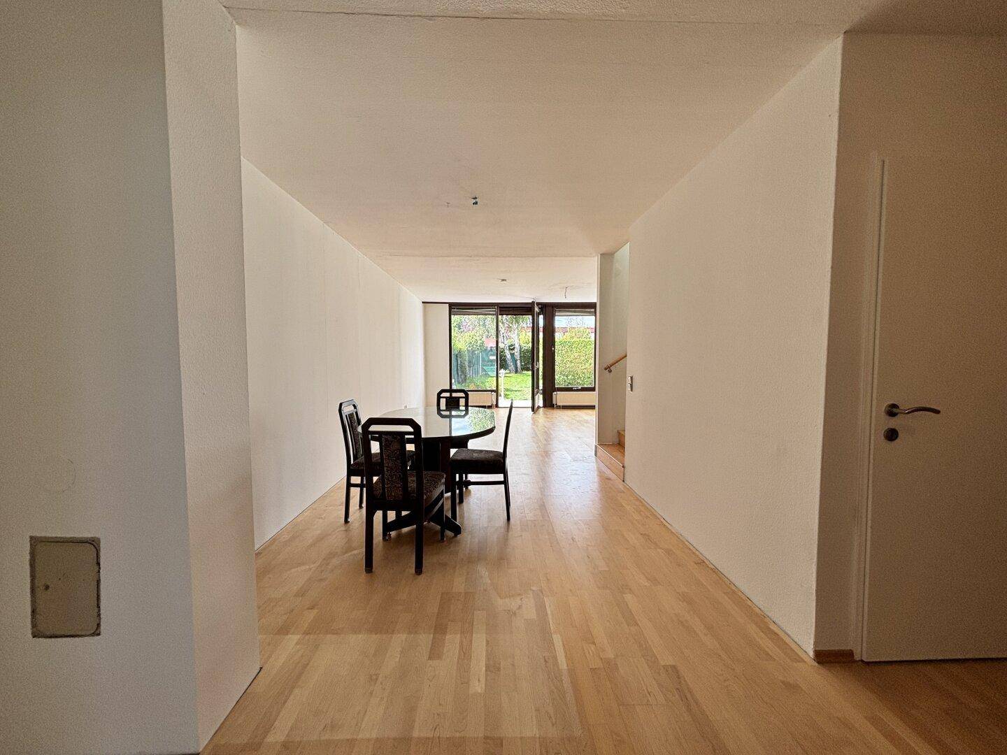 Langer Wohn- und Essbereich mit Parkettboden und Blick auf die Gartenterrasse.