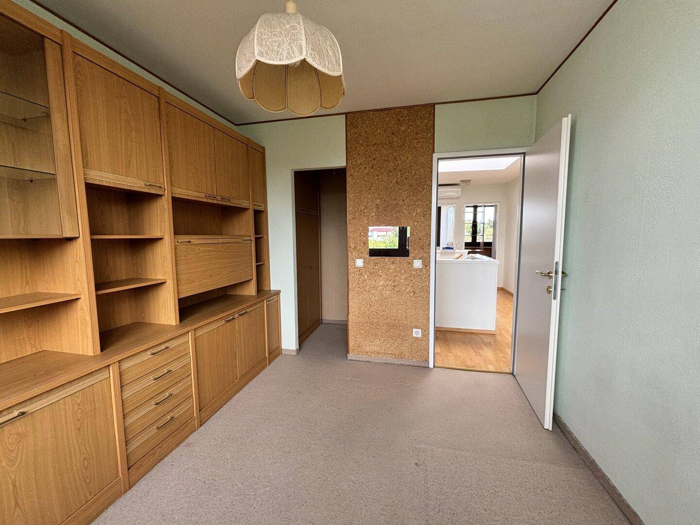 Arbeitszimmer mit Einbauschränken, Regalen und Blick in den Flur.
