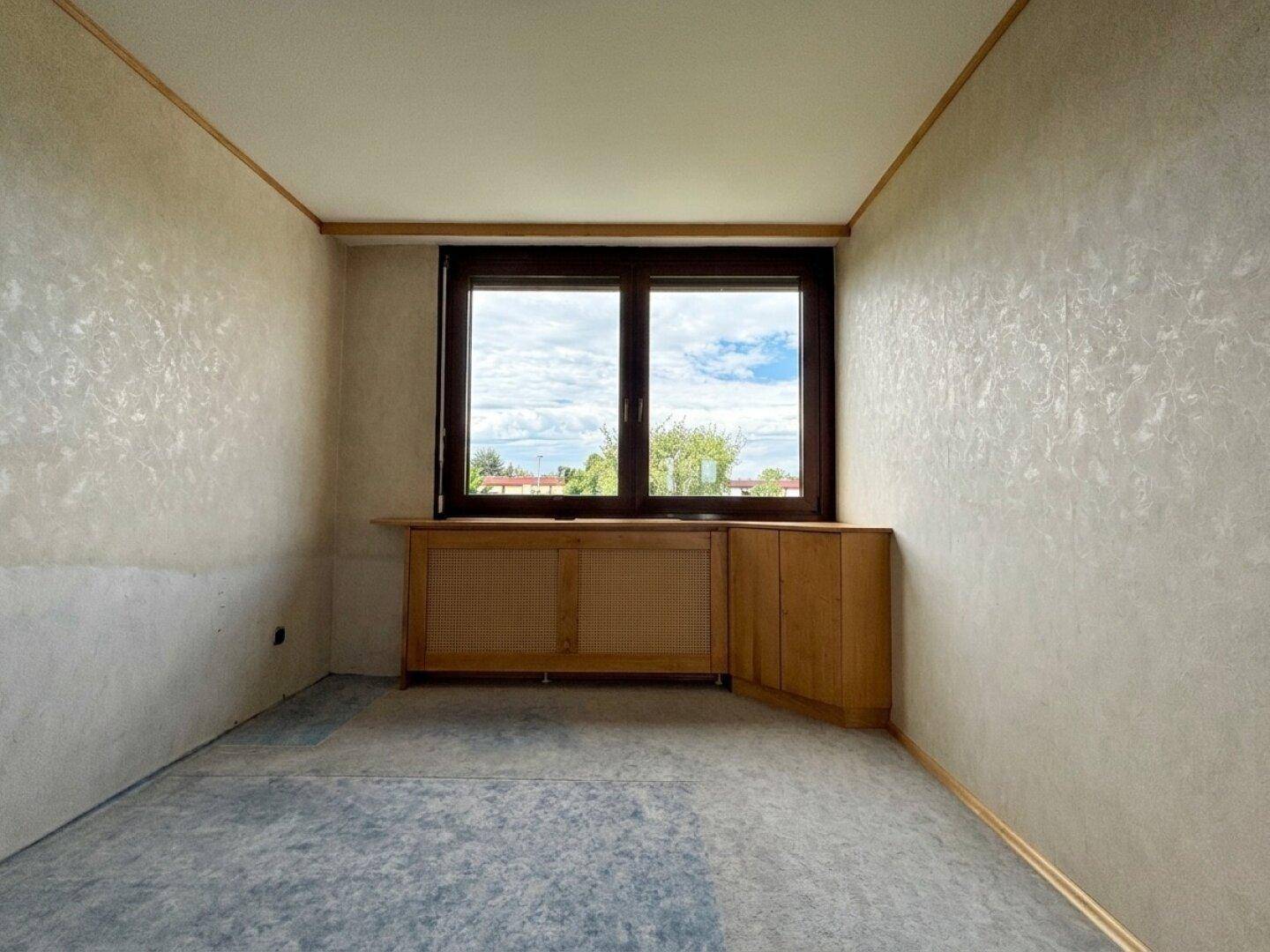 Schlafzimmer mit Fenster, Teppichboden und Holzverkleidung an den Wänden.