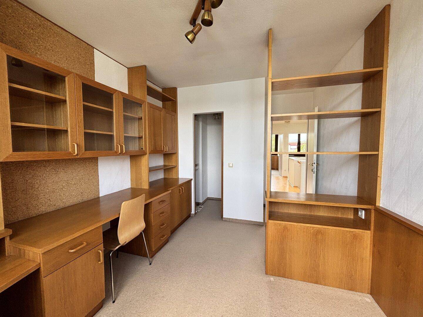 Geräumiges Arbeitszimmer mit Holzregalen und Schreibtischbereich.