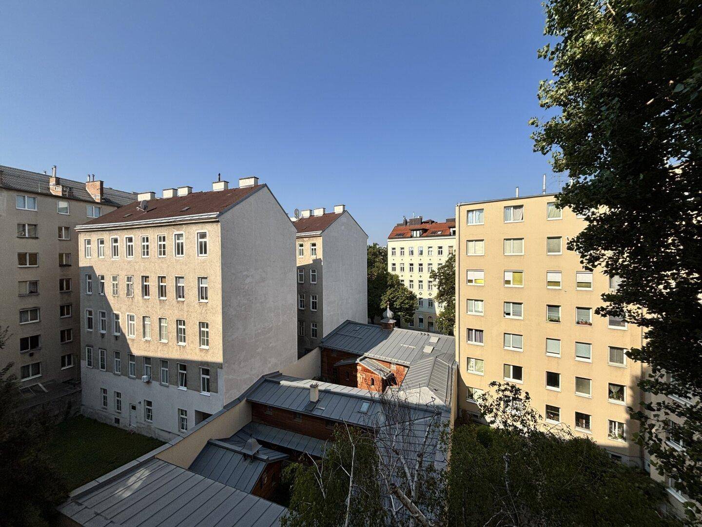 Blick auf die umliegenden Wohngebäude und grüne Bäume an einem sonnigen Tag.