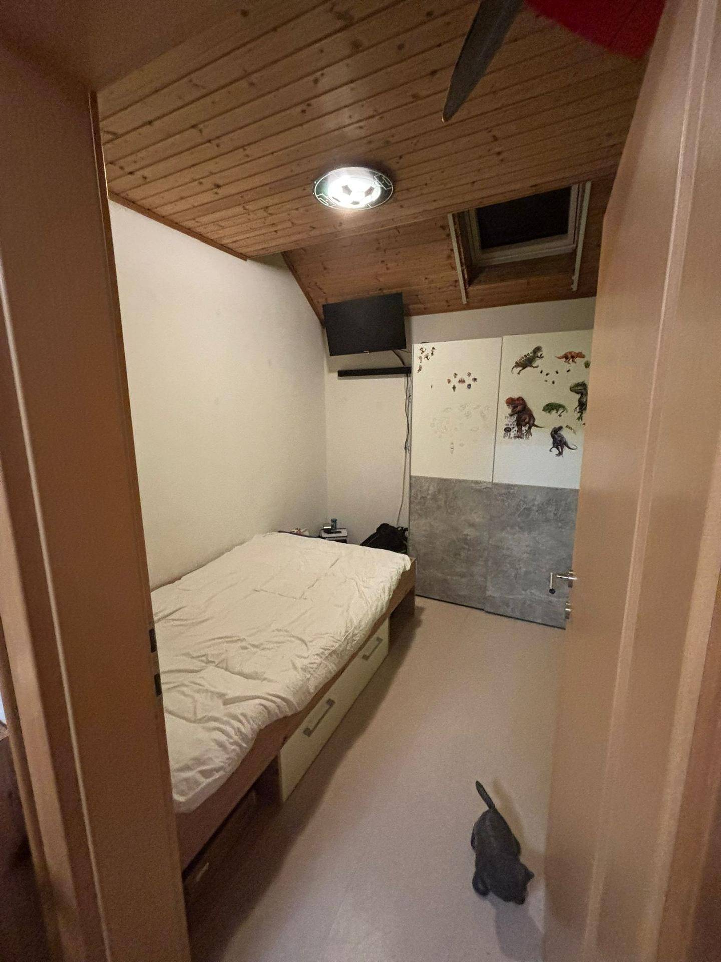 Gemütliches Schlafzimmer im Dachgeschoss mit Holzdachschräge, Bett mit Stauraum und Dachfenster.