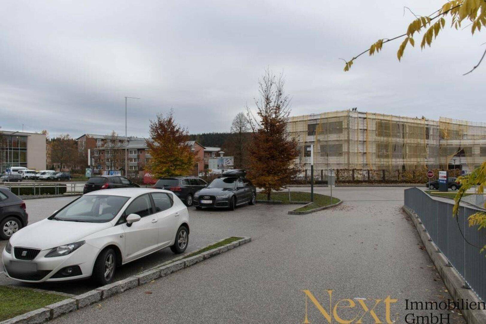 Weiterer Blick auf einen Parkplatz mit Fahrzeugen und einem im Bau befindlichen Gebäude im Hintergrund.