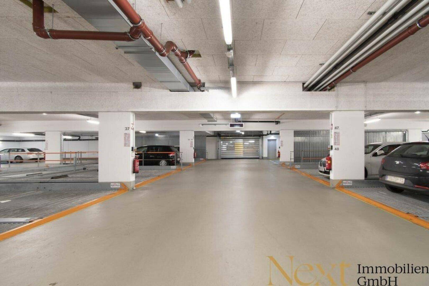 Tiefgarage mit markierten Stellplätzen und guter Beleuchtung, bietet sichere Parkmöglichkeiten.