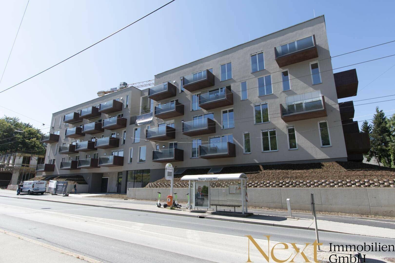 Neubauwohngebäude an einer Straße mit zahlreichen Balkonen und moderner Architektur.