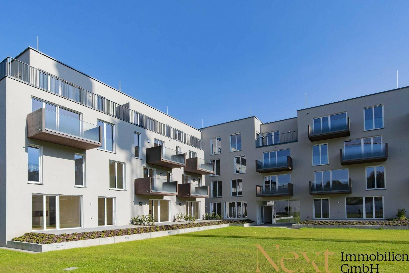 Moderne Wohnanlage mit mehreren Balkonen und gepflegter Rasenfläche im Außenbereich.
