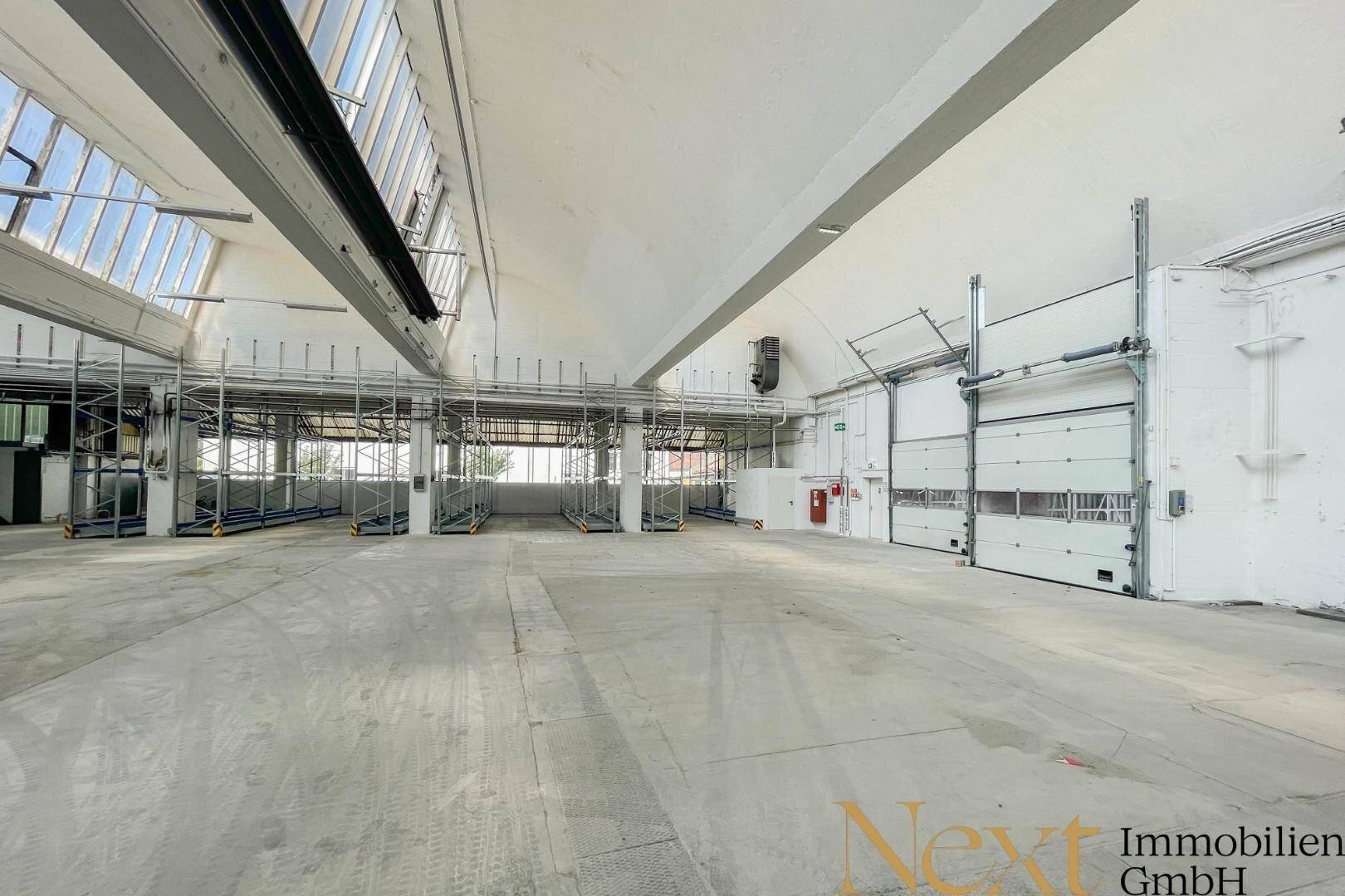 Helle Lagerhalle mit mehreren Rolltoren und hohen Decken, bereit für den Warenumschlag und Lagerung.