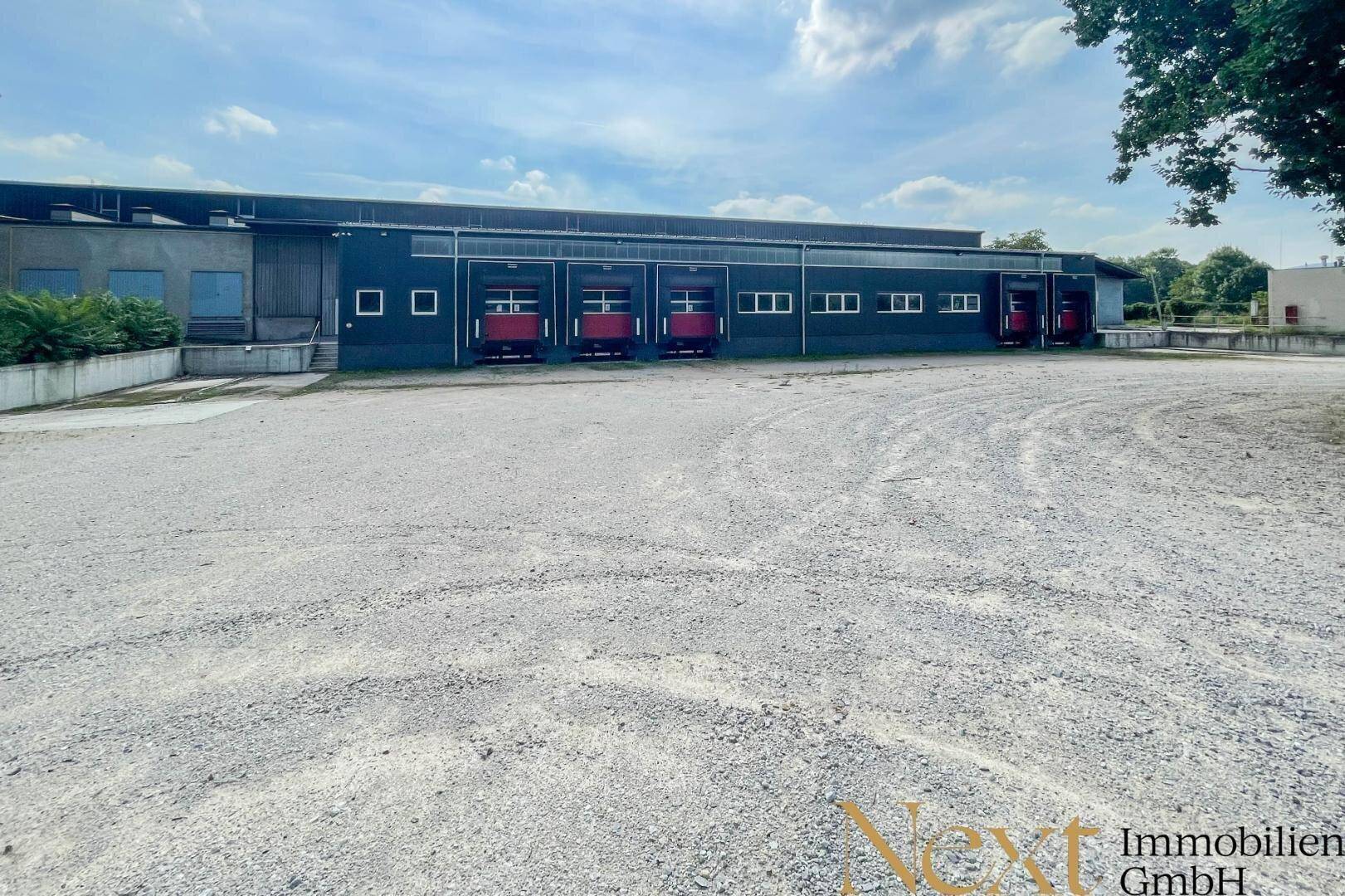 Weitläufige Außenansicht einer Industriehalle mit mehreren Laderampen und großem Vorplatz.