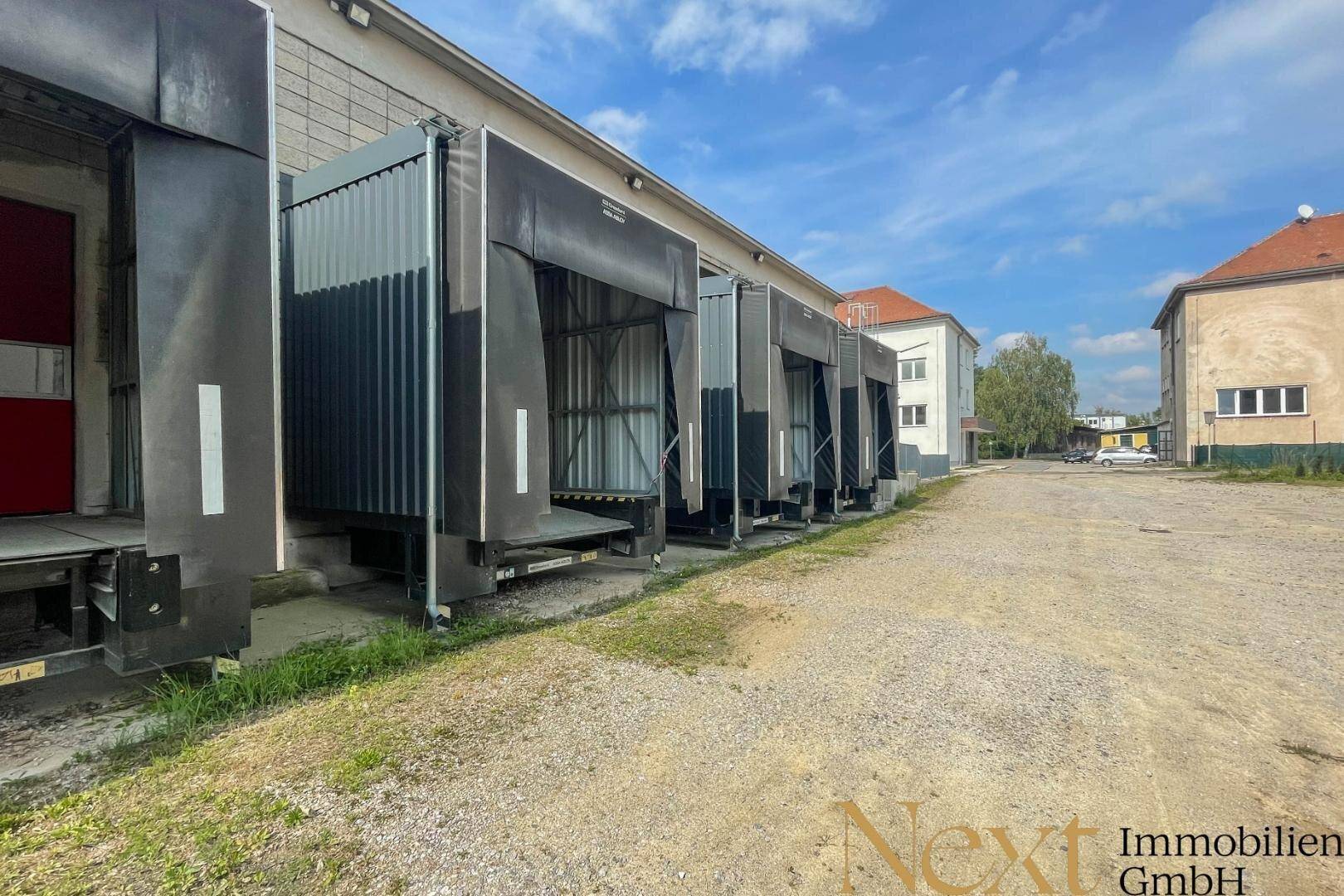 Außenansicht der Laderampen einer Industriehalle unter blauem Himmel, bereit für den Güterverkehr.