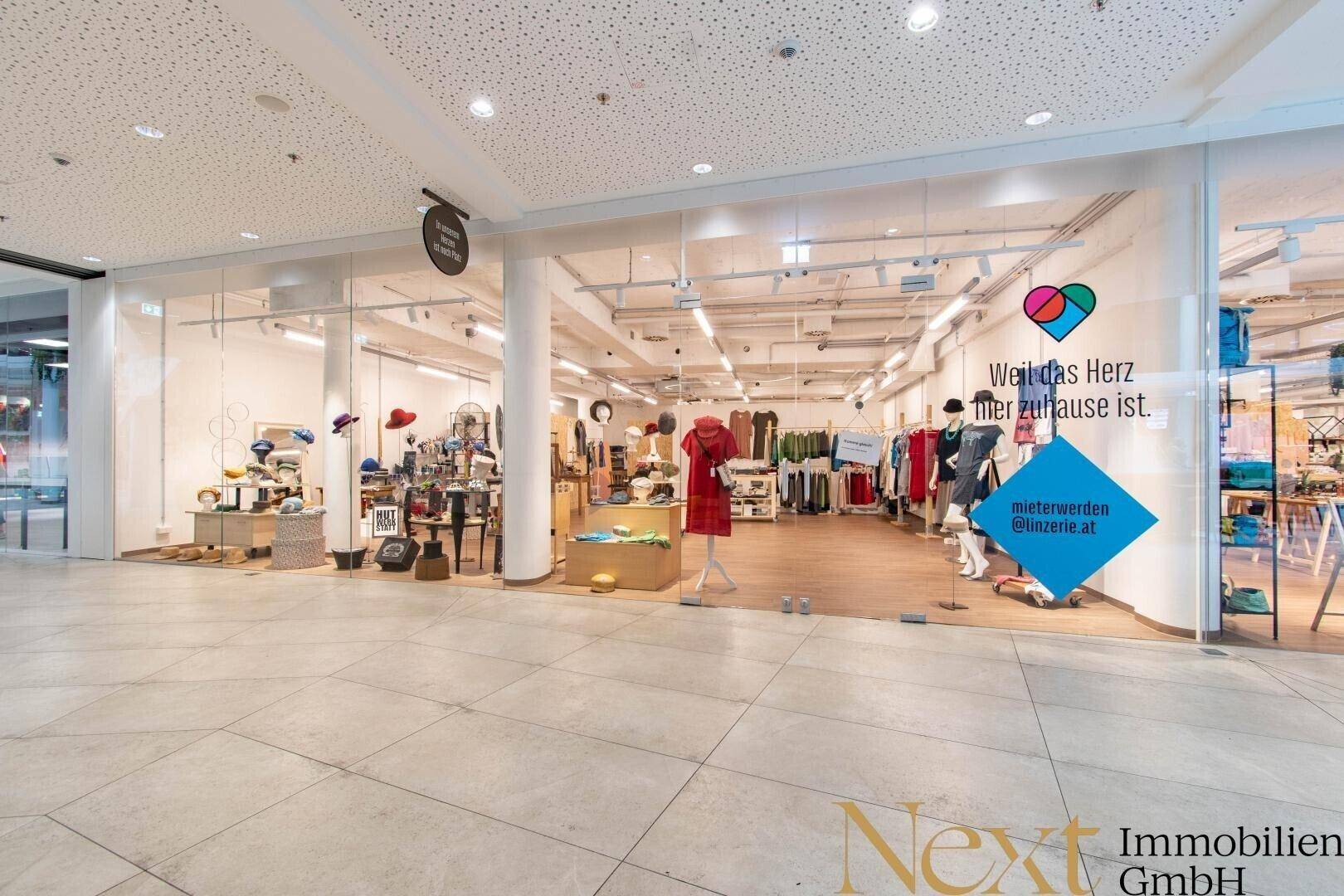 Weitläufiger Einzelhandelsraum mit großen Schaufenstern und moderner Inneneinrichtung in einem Einkaufszentrum.