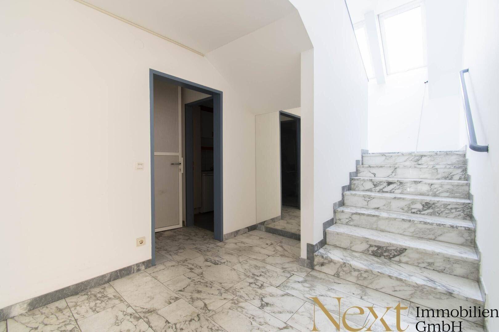 Eingangsbereich mit elegantem Marmorboden und einer Treppe, die zu den oberen Etagen führt.