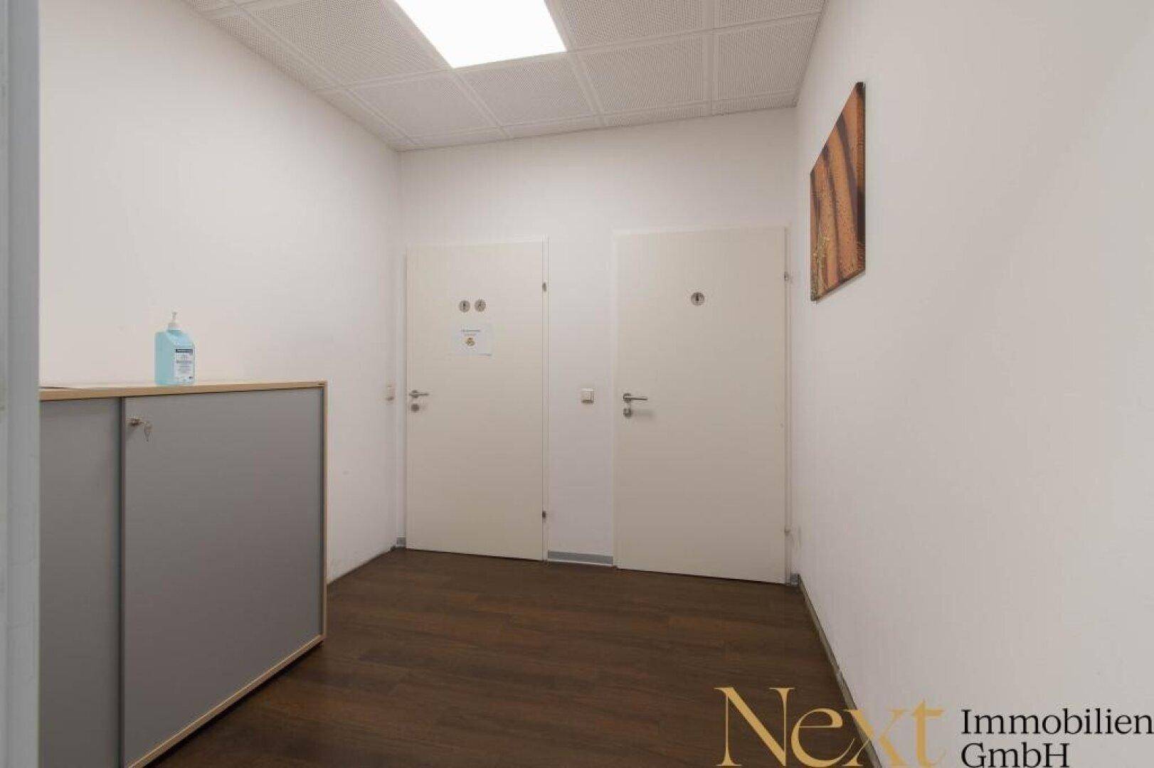 Schlichter Flur mit dunklem Holzboden und zwei Türen, ausgestattet mit einem praktischen Schrank.