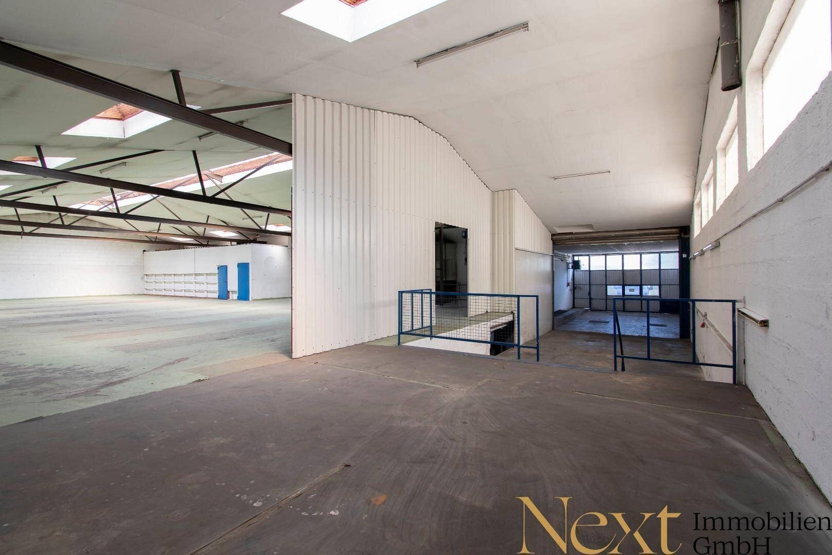 Geräumige Lagerhalle mit Rampe, Rolltor und Oberlichtern, ideal für gewerbliche Nutzung.