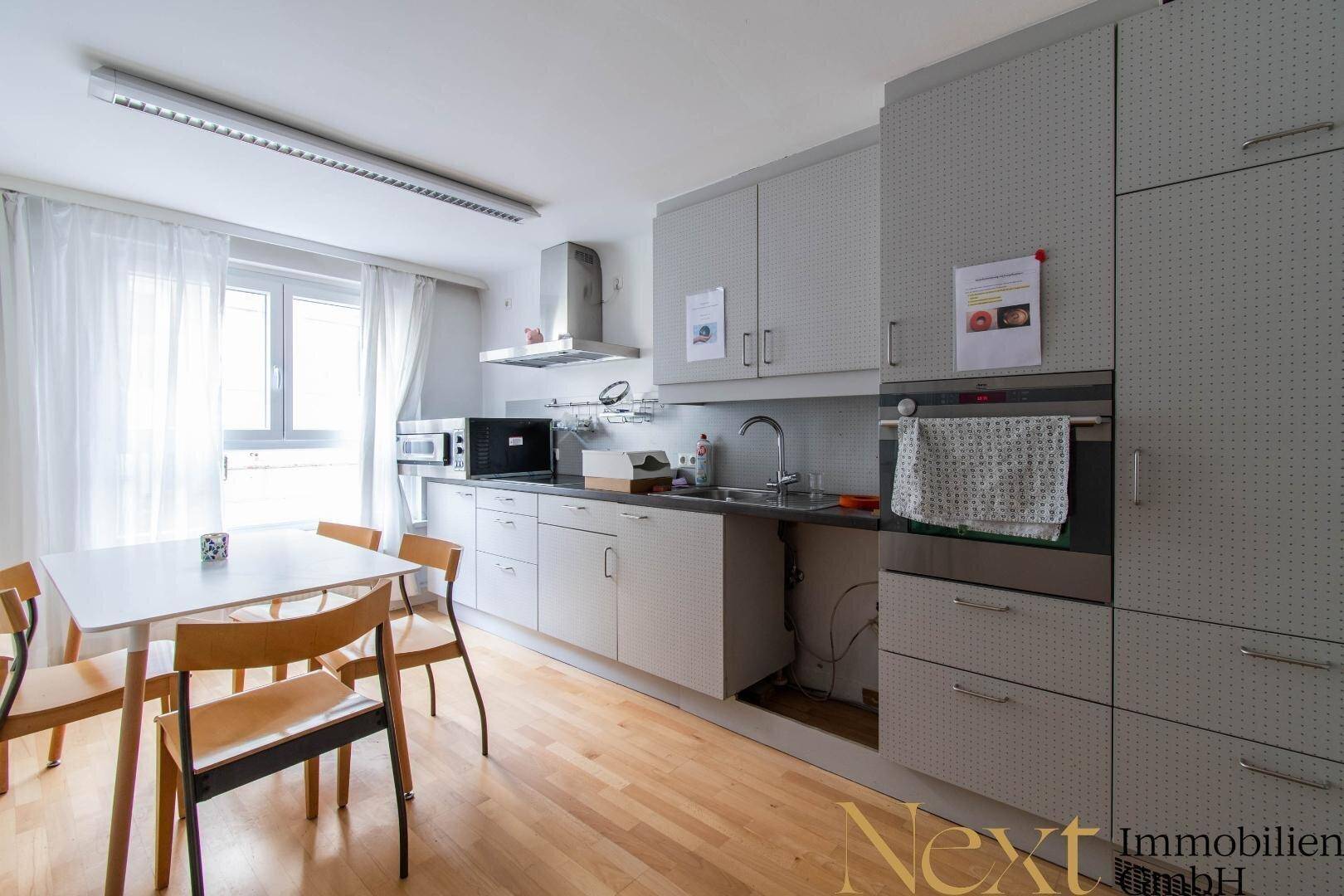 Funktionale Küche mit Esstisch, modernen grauen Schränken und Fenster, ideal für den täglichen Gebrauch.