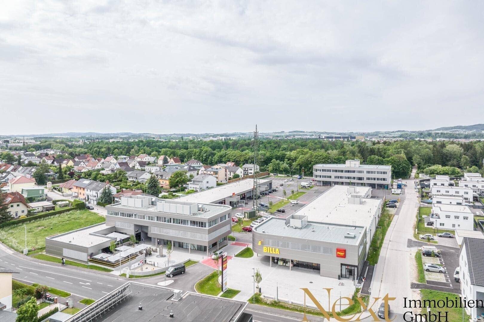 Luftaufnahme eines modernen Gewerbeparks mit mehreren Gebäuden, Parkplätzen und viel Grünfläche.