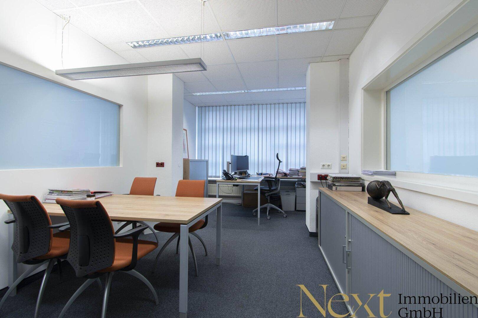 Modernes Büro mit Besprechungstisch, Teppichboden und funktionaler Einrichtung, ideal für Teamarbeit.