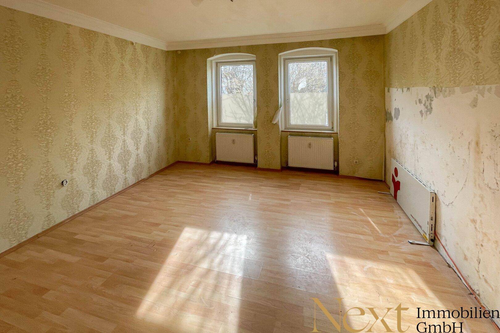Geräumiges Zimmer mit Laminatboden und zwei Fenstern, ideal für eine individuelle Gestaltung.